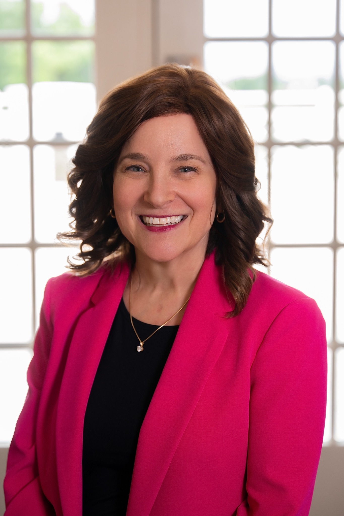 Dr. Susan Bernstein wearing a magenta blazer in front of bright windows